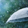 Transparent umbrella under heavy rain against water drops splash background. Rainy weather